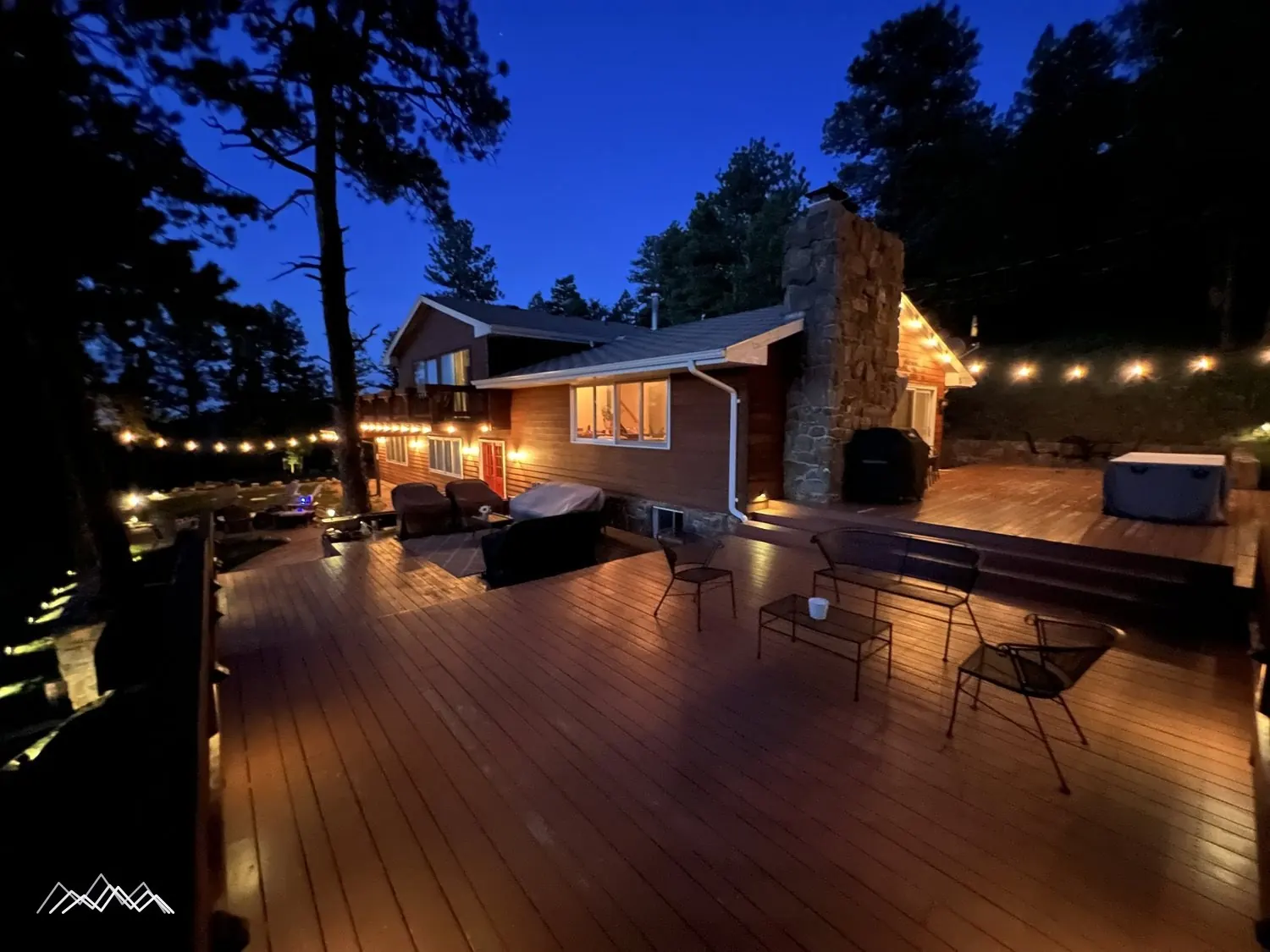 The house and deck lit with string lights at blue hour
