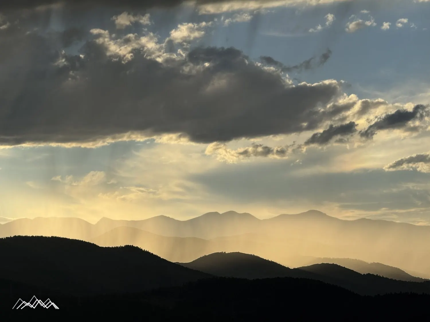 Shafts of late light breaking through cloud over the foothills