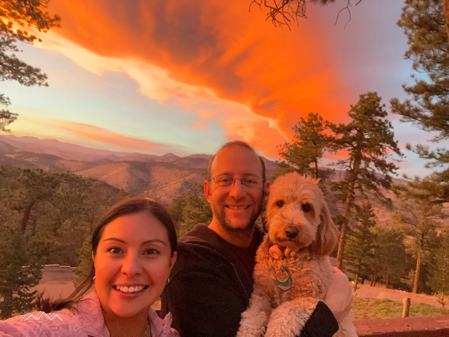 Mily and Danny Dodson with their dog under a fiery pink sunset sky