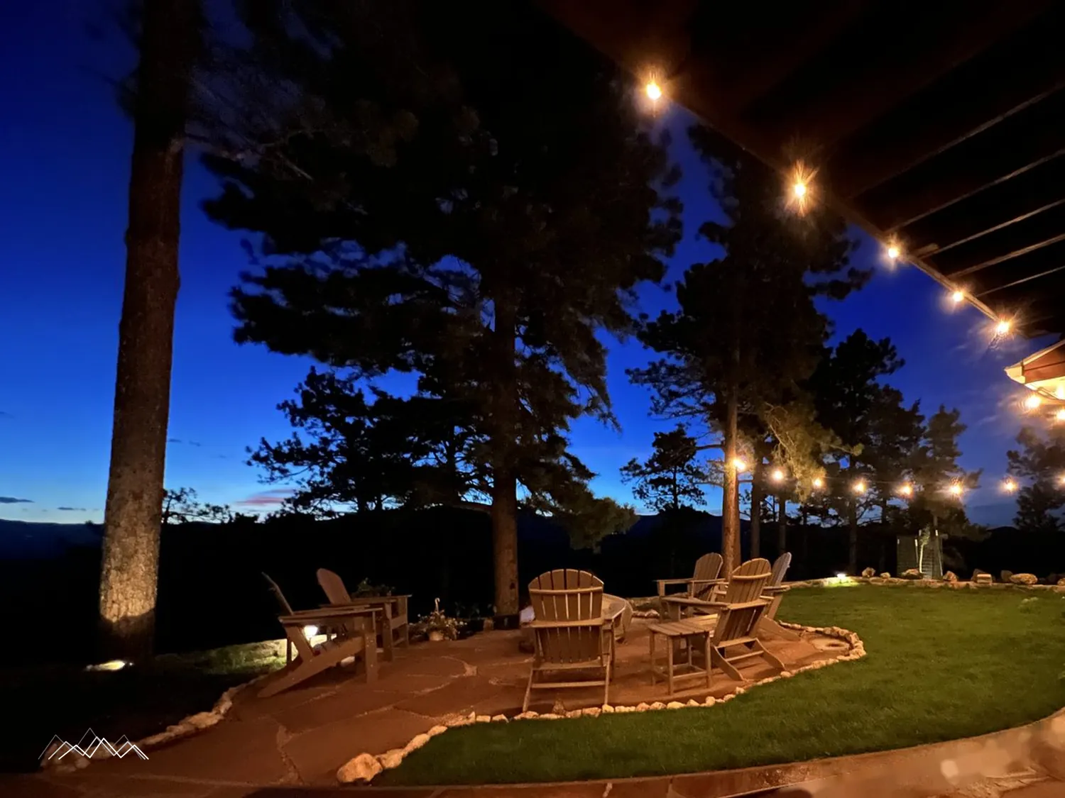 The flagstone patio and lawn under glowing string lights at blue hour