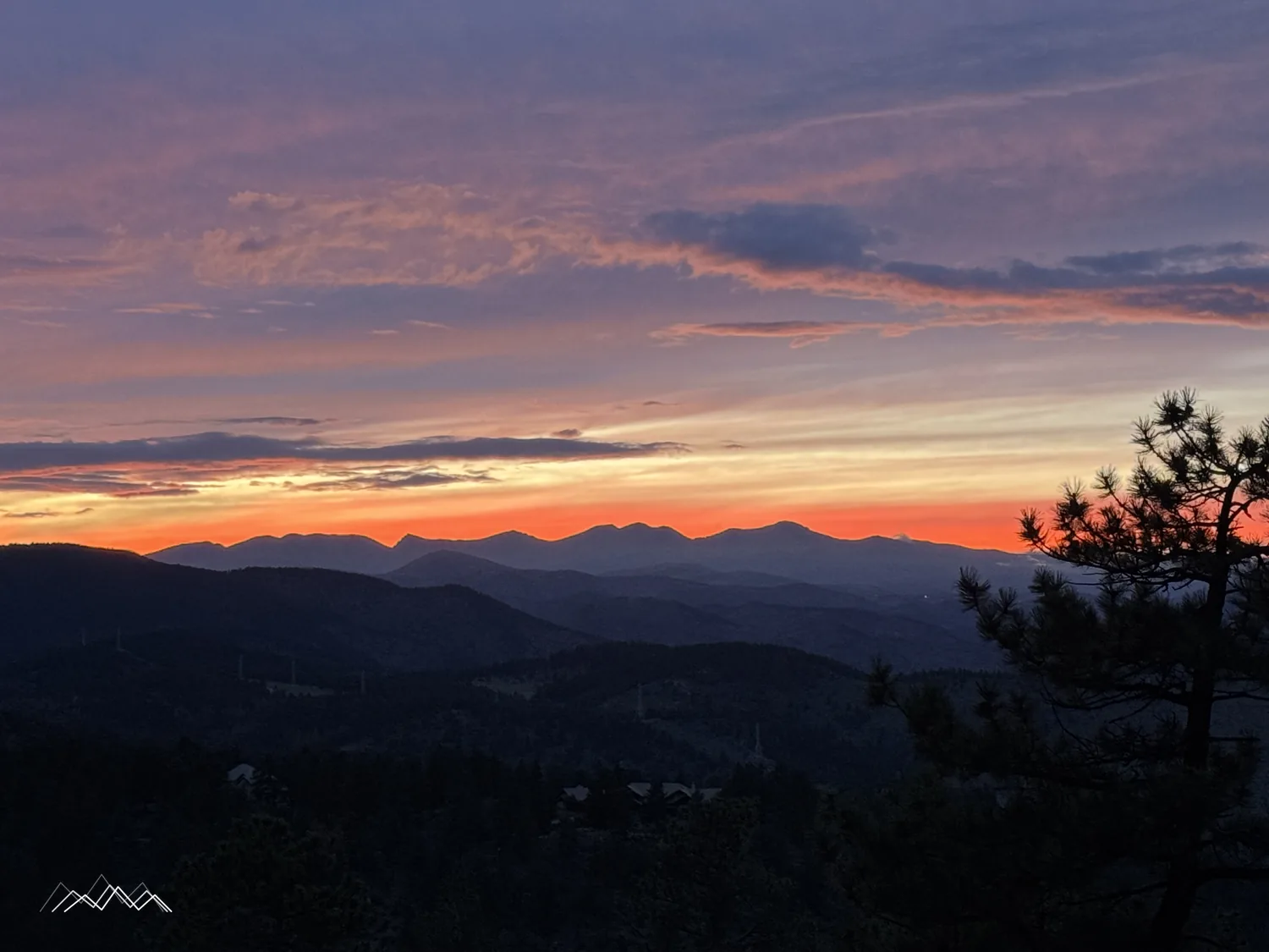 Rosa und violette Abendwolken über den Indian Peaks und gestaffelten Hügeln