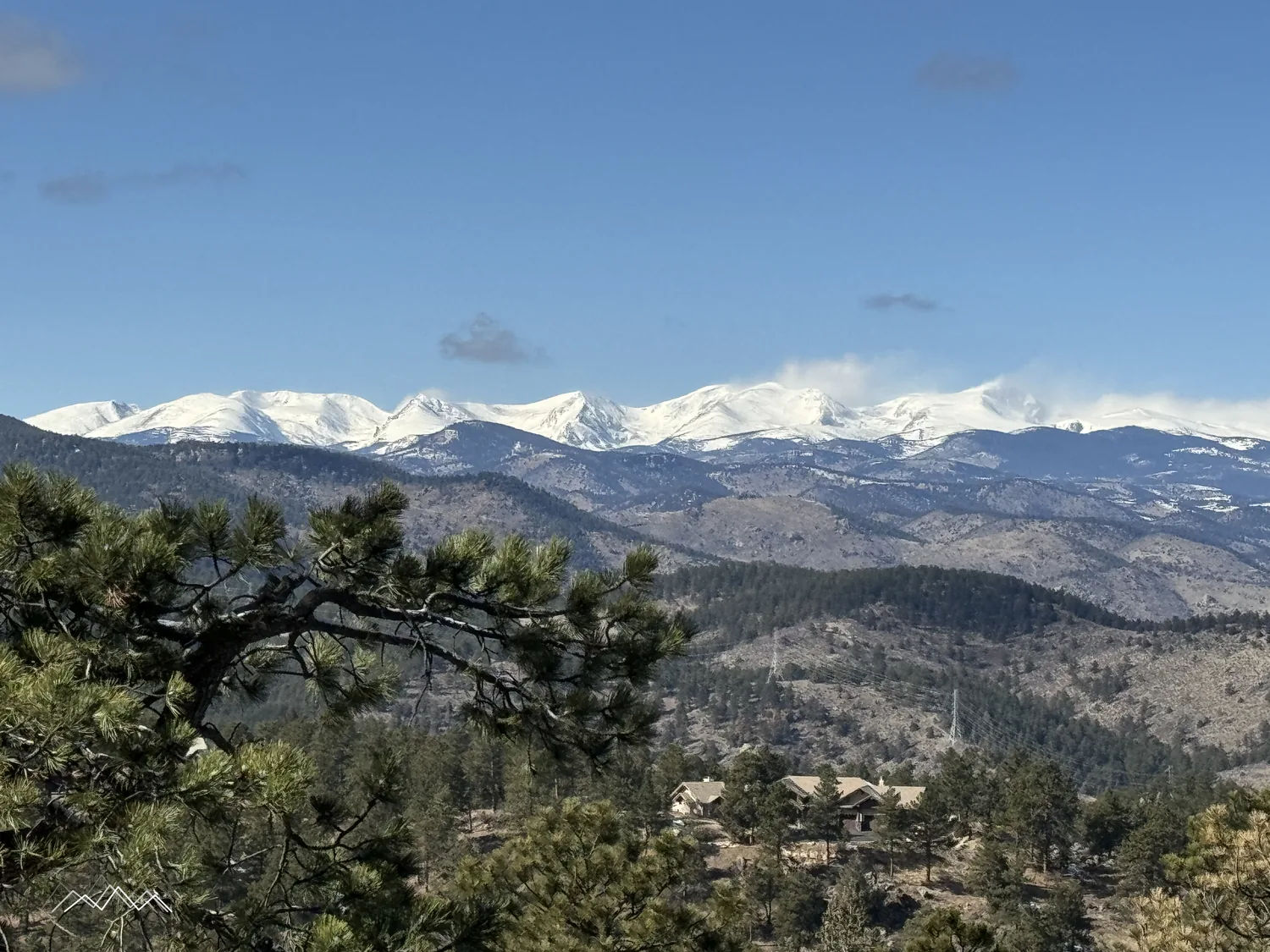 Leuchtend verschneite Indian Peaks unter blauem Himmel hinter bewaldeten Hügeln