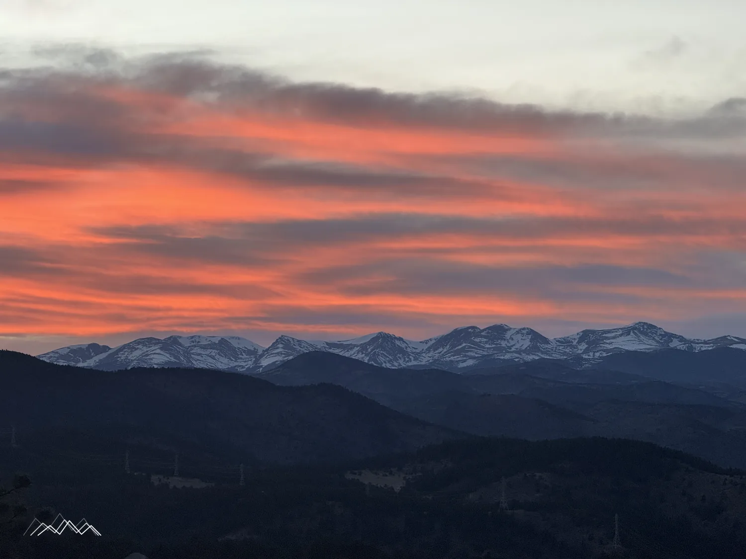 Des nuages striés de rouge et d’orange au-dessus des Indian Peaks enneigés au coucher du soleil
